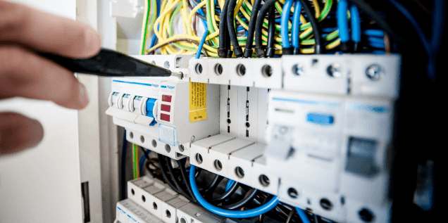 Technicien CRELEC HVAC Solutions effectuant un contrôle électrique sur une installation, avec instruments de mesure et équipements de sécurité